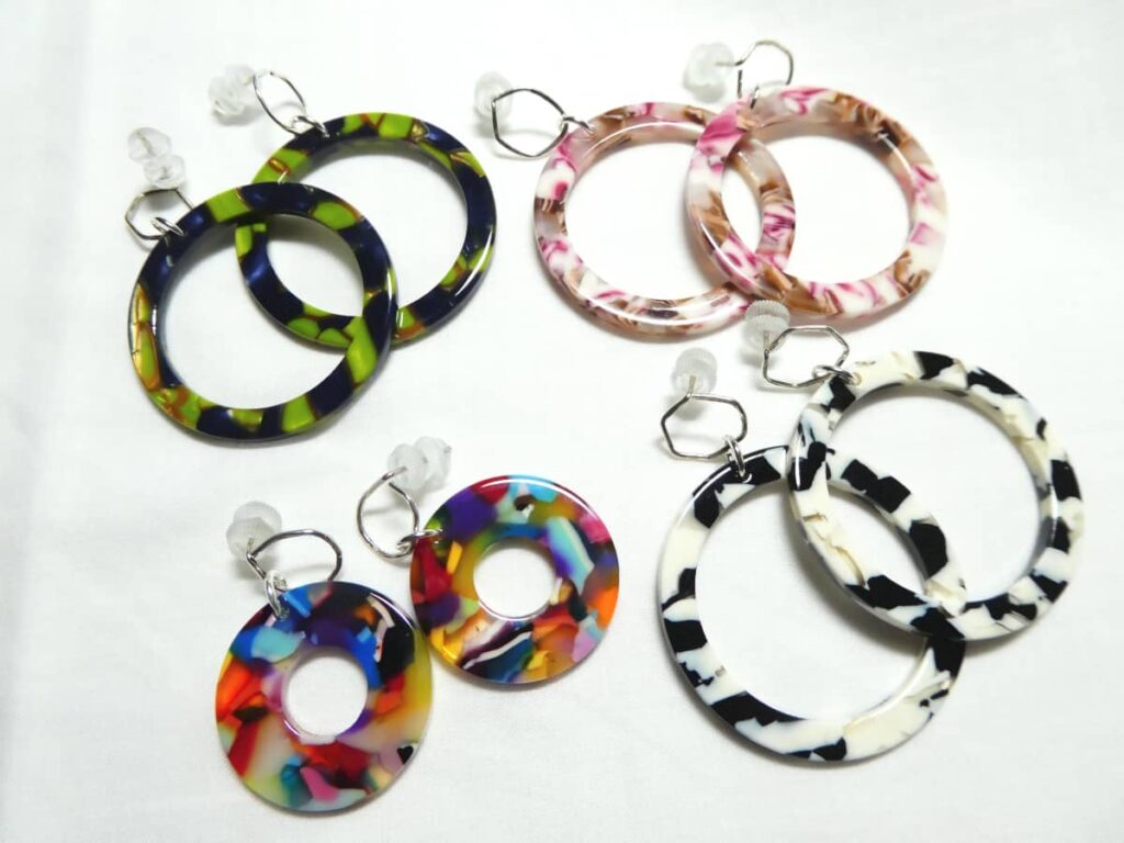 Les clous d'oreille en argent martelé et poli avec anneaux en acétate de cellulose.